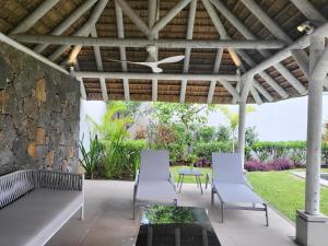 un patio con sillas blancas y una pared de piedra. en Villa de Luxe à Grand Baie avec piscine V12, en Grand Baie