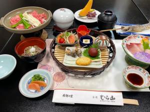 einen Tisch mit Teller und Schalen mit Lebensmitteln in der Unterkunft Ryokan Murayama in Takayama