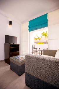 a living room with two wicker couches and a television at St.Lachlan Hotel & Suites in Negombo