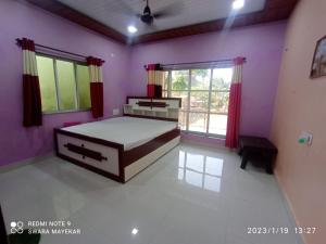 um quarto com paredes roxas, uma cama e uma janela em Priyansh Home stay em Harihareshwar