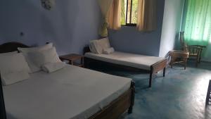 a room with two beds and a chair and a window at Leijay Garden Retreat in Galle