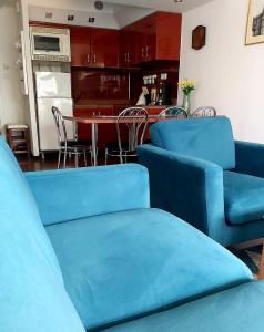 a living room with blue couches and a kitchen at Leśna Przystań in Rewal