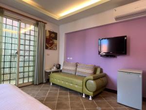 een slaapkamer met een bank en een tv aan een paarse muur bij Xing Yu Inn in Eluan