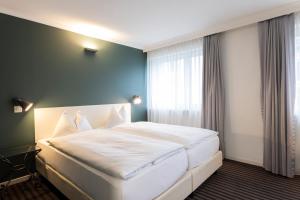 a bedroom with a large white bed with a window at Self Check-In Hotel David 22 in St. Gallen