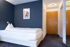 sypialnia z niebieskimi ścianami i dużym białym łóżkiem w obiekcie Self Check-In Hotel David 22 w mieście St. Gallen