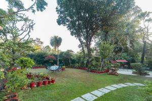 un jardín con mesas, sillas y plantas en SaffronStays Doon Garden Villa - near Doon School and Mall Road en Dehradun