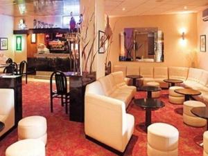 un vestíbulo con sofás y mesas blancos y un bar en HOTEL DE LISIEUX, en Lourdes