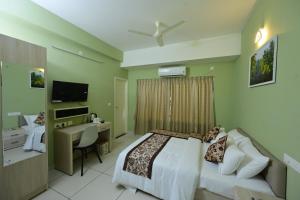 a bedroom with a bed and a desk and a television at RG's The 4th Residency in Trivandrum