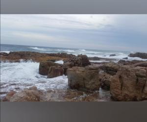 una playa con rocas y el océano con olas en Tropical 4 Bedroom 3 bathroom 8 to 10 sleeper Holiday Getaway en Port Edward