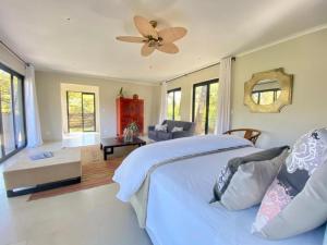 a bedroom with a white bed and a ceiling fan at Crocodile Sands River Lodge in Nelspruit