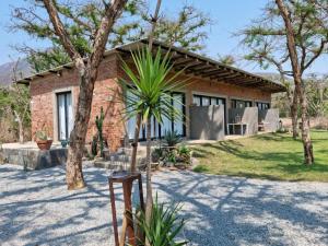 uma casa de tijolos com uma palmeira em frente em Crocodile Sands River Lodge em Nelspruit