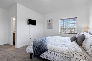 - une chambre blanche avec un lit et une télévision à écran plat dans l'établissement Village Townhouse 2, à Boise