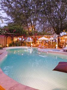 a large swimming pool with tables and umbrellas at Villa Almarik Resort in Gili Trawangan