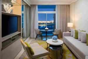 a living room with a couch and a television at Beach Rotana – All Suites in Abu Dhabi