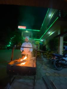 Un uomo che cucina sopra un fuoco in una griglia di notte di Hotel Greenlight a Chitwan
