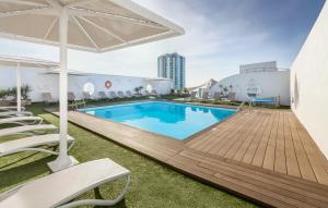 una gran piscina con sillas y sombrilla en Hotel Lancelot en Arrecife