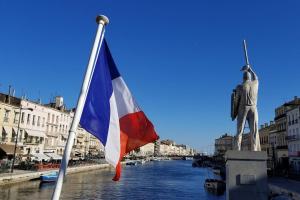 Una bandiera su un palo accanto a una statua di Appartement T4 Centre Ville Séte tout confort 3 chambres a Sète