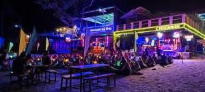 un grupo de personas sentadas en mesas en una calle por la noche en Phangan Mantra Inn, en Haad Rin