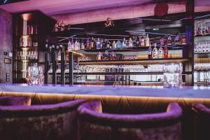 a bar with purple bar stools and bottles of alcohol at GLEMM by AvenidA Superior Hotel & Residences in Saalbach Hinterglemm