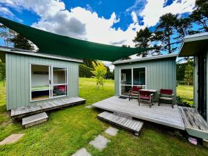 a green house with a table and chairs on a field at Tui Ridge Eco Cabins in Aongatete