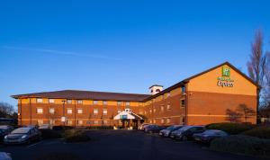 Holiday Inn Express Taunton East, an IHG Hotel في تونتون: مبنى كبير من الطوب مع سيارات تقف في موقف للسيارات