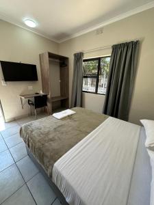 um quarto com uma cama grande, uma secretária e uma janela em Ecomotel Louis Botha em Joanesburgo