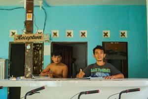 deux hommes debout derrière un comptoir dans une pièce dans l'établissement Ping Pong homestay Gili Trawangan, à Gili Trawangan