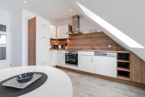 una cocina con armarios blancos, una mesa y una escalera en Nordseeperle, en Greetsiel