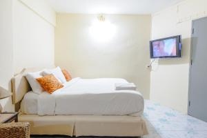 a bedroom with a bed and a tv on a wall at High5 Guesthouse in Pattaya
