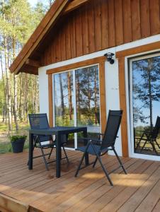 a patio with two chairs and a table on a deck at Żurawia Polana in Świętajno