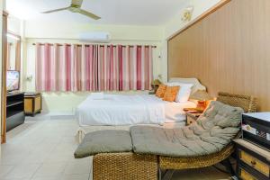 a bedroom with a bed and a couch and a tv at High5 Guesthouse in Pattaya