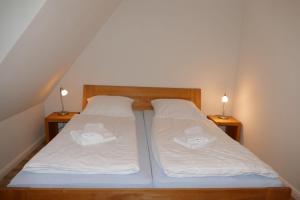 1 Schlafzimmer mit 2 Betten mit weißer Bettwäsche und Lampen in der Unterkunft Hus Hiddensee in Vitte