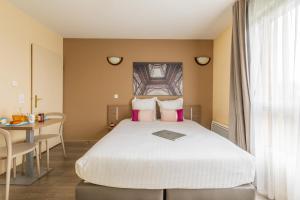 een slaapkamer met een bed met een laptop erop bij Zenitude Hôtel-Résidences Magny-les-Hameaux in Magny-les-Hameaux