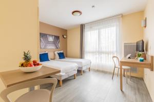 ein Hotelzimmer mit 2 Betten und einem Tisch mit einer Obstschale in der Unterkunft Zenitude Hôtel-Résidences Magny-les-Hameaux in Magny-les-Hameaux