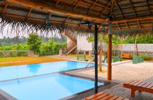 a large swimming pool with a pavilion and a picnic table at Luxury Rooms Cinnamon Nature Resort in Beruwala
