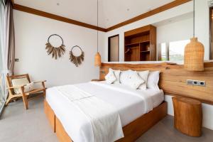 a bedroom with a large bed and a chair at Villa Noemie by BaliSuperHost in Ubud