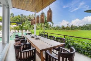 an outdoor dining room with a wooden table and chairs at Villa Noemie by BaliSuperHost in Ubud
