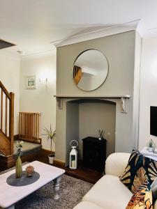 a living room with a white couch and a mirror at Cosy Heather Cottage in Ashbourne
