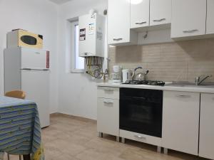 cocina con armarios blancos y fogones negros en Apartamente la rezidenta noua ideale vacanze job etc en Chişoda