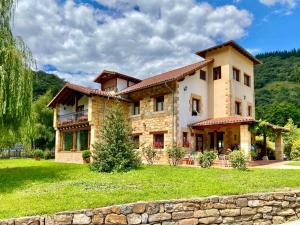 a large house in a field with a stone wall at Posada El Hoyal in Pesaguero-La Parte