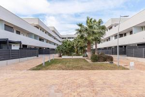 a courtyard of a building with trees and palm trees at Apartamento La cala in L'Ametlla de Mar