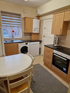 a kitchen with a white table and a table and chairs at Primary bedroom with king size bed in 3 rooms apartment in London