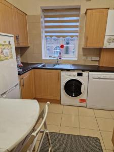 a kitchen with a washing machine and a sink at Primary bedroom with king size bed in 3 rooms apartment in London