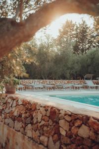 a pool with tables and chairs next to a stone wall at Il Villaggetto in Neviano