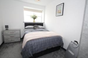 ein kleines Schlafzimmer mit einem Bett und einem Fenster in der Unterkunft High Tide apartment with sea views in Whitley Bay