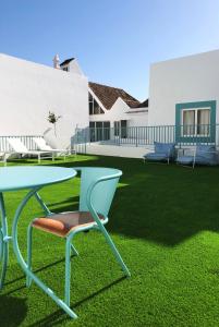 a green table and a chair on a lawn at A Muralha in Tavira