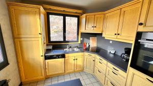 a kitchen with wooden cabinets and a sink and a window at Gîte Le Pingu - spacieux, calme, plein sud - cabine sauna - 8 personnes in La Bresse