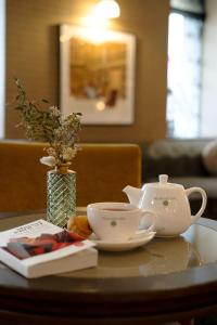 a table with two tea cups and a vase at Hotel Litteraire Le Swann, BW Premier Collection in Paris