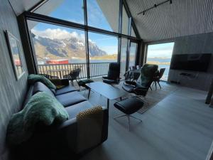 a living room with a couch and chairs and a large window at Rorbuleilighet Lysøysundet 1G in Henningsvær