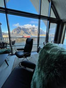 a room with chairs and a view of the mountains at Rorbuleilighet Lysøysundet 1G in Henningsvær